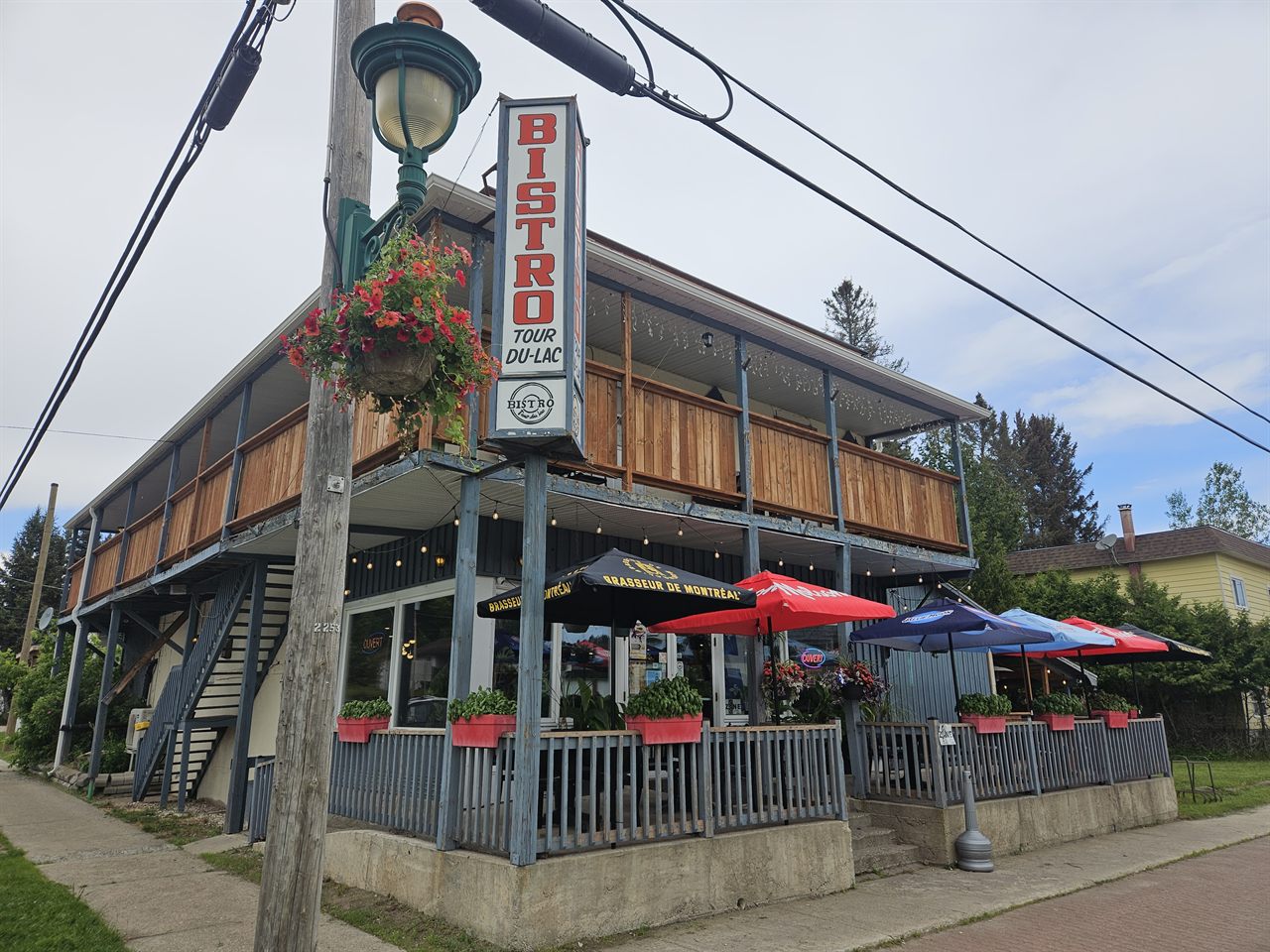 Le Bistro tour du lac vu de la rue : façade en bois, terrasse et grande enseigne rouge